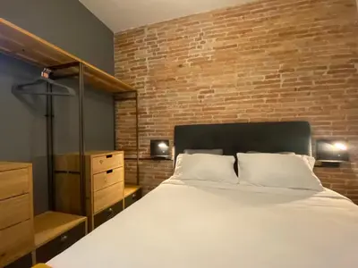 a bedroom with a large bed and a brick wall at Cosy Urban Oasis 1BD in Poble Sec By MyRentalHost in Barcelona