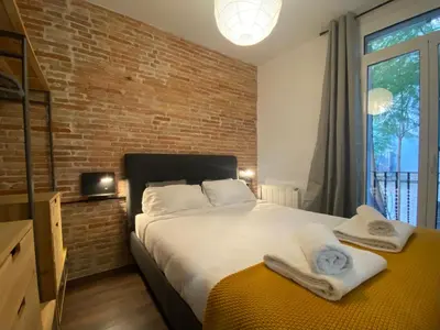 a bedroom with a large bed and a brick wall at Cosy Urban Oasis 1BD in Poble Sec By MyRentalHost in Barcelona