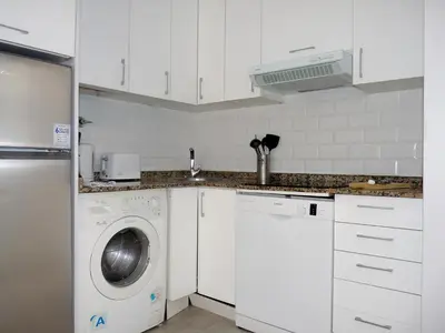 a white kitchen with a washer and dryer at MarBarcelona Apartments Mas in Hospitalet de Llobregat
