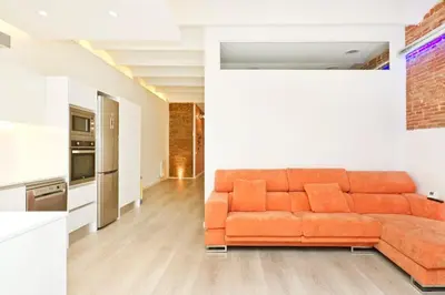 an orange couch in a living room next to a kitchen at Roós, design loft near the sea. in Barcelona