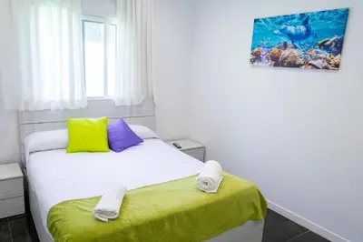 a bedroom with a white bed with yellow and purple pillows at VILLA 5 PLAYA A 2 MINUTOS in Castelldefels