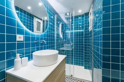 a blue tiled bathroom with a sink and a mirror at Stylish Apartment near Plaça España in Barcelona