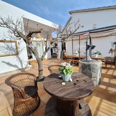 a patio with a table and chairs and a tree at Au Jardin d'Armand in Sant Pere de Ribes
