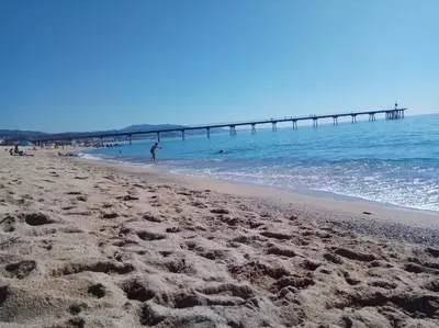 a sandy beach with a pier in the water at Apartamento PB 30min Sagrada Familia, 10 min playa in Badalona