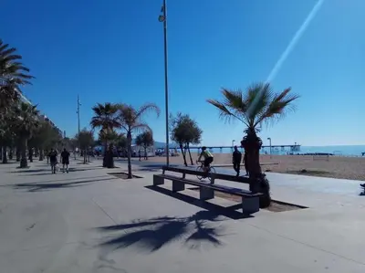 a park with a bench and palm trees on the beach at Apartamento PB 30min Sagrada Familia, 10 min playa in Badalona