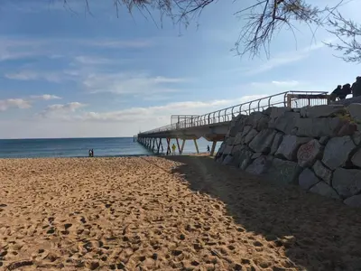 a sandy beach with a pier and the ocean at Apartamento P1 30min Sagrada Familia, 10 min playa in Badalona