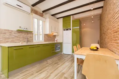 a kitchen with green cabinets and a wooden table at Stay Barcelona Charming Gracia in Barcelona