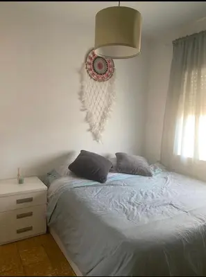 a bedroom with a bed and a lamp and a window at Cozy apartament in Barcelona