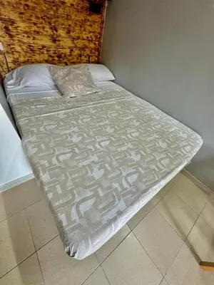 a bed with a comforter on it in a room at Nuevos Apartamentos frente al mar y a la playa in Castelldefels