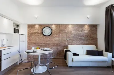 a living room with a couch and a clock on a brick wall at AB Paral·lel Spacious Apartments in Barcelona