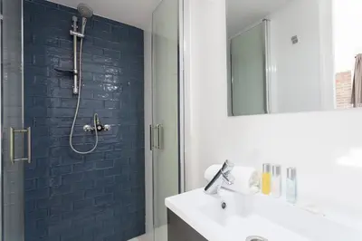 a bathroom with a sink and a shower with blue tiles at AB Paral·lel Spacious Apartments in Barcelona