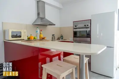 a kitchen with a white counter and red cabinets at Bcn - Poble Nou in Barcelona