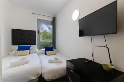 a room with two beds and a flat screen tv at Fira Suites - Habitaciones privadas en Apartamento compartido in Hospitalet de Llobregat