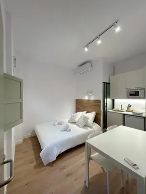 a white bedroom with a bed and a table at SD Habitación céntrica con baño y Kitchenette in Terrassa