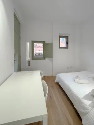 a white room with two beds and a table at SD Habitación céntrica con baño y Kitchenette in Terrassa