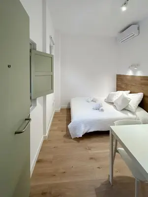 a white bedroom with a bed and a table at SD Habitación céntrica con baño y Kitchenette in Terrassa
