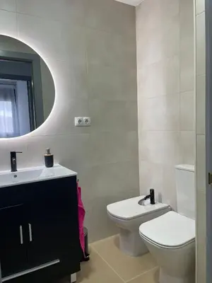 a bathroom with a toilet and a sink and a mirror at Luminoso dúplex con parking in Terrassa