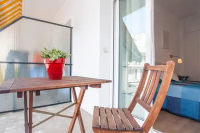 a wooden table with a potted plant and a chair at Hola! - Sitges Centric Apartment in Sitges