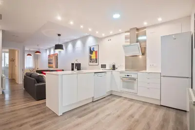 a kitchen with white cabinets and a living room at Barcelona Eixample in Barcelona
