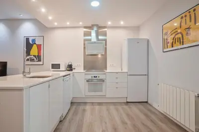 a kitchen with white cabinets and a refrigerator at Barcelona Eixample in Barcelona