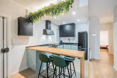 a kitchen with a wooden counter top and green bar stools at Barcelona Eixample in Barcelona