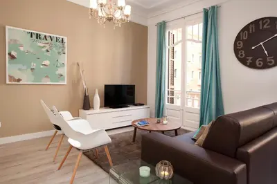 a living room with a couch and a table and a clock at Click&Flat Seneca Suites in Barcelona