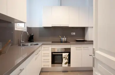 a kitchen with white cabinets and a sink at Click&Flat Seneca Suites in Barcelona