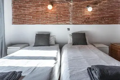 two beds in a room with a brick wall at Apartamento La Boqueria 4 in Barcelona