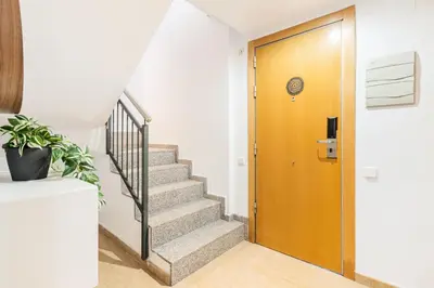 a hallway with stairs and a wooden door at AB Besòs River Apartment in Sant Adria de Besos
