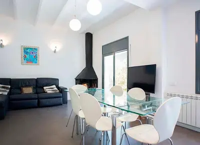 a dining room with a glass table and white chairs at Tu Casa en Barcelona in Sant Cugat del Vallès