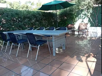 a table with chairs and an umbrella on a patio at Casa en Castelldefels a 5 min de la playa in Castelldefels