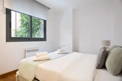 a white bedroom with a large bed and a window at Les Corts Exclusive Apartments by Olala Homes in Barcelona