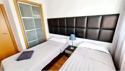 two twin beds in a room with a lamp on a table at MERCE APARTMENT FORUM BARCELONA in Sant Adria de Besos