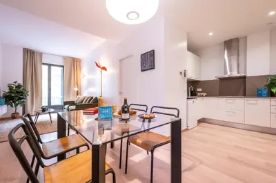 a dining room and living room with a glass table and chairs at Sweett - Casa Girona in Barcelona