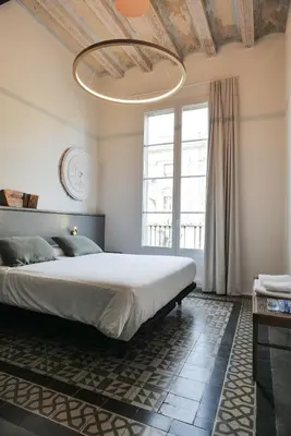 a bedroom with a large bed and a chandelier at Hostal Porxos Garden in Barcelona