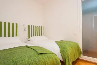 a bedroom with two beds and a green blanket at Autèntic Barcelona Monumental in Barcelona