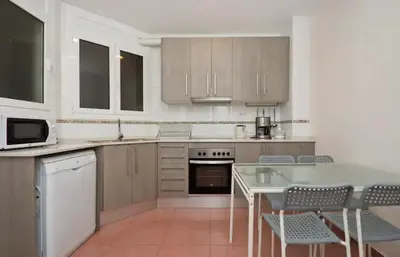 a kitchen with white cabinets and a table and chairs at Autèntic Barcelona Monumental in Barcelona