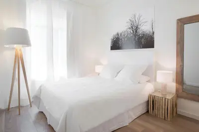 a white bedroom with a white bed and two lamps at Casanova Charm 4BDR Apartment in Barcelona