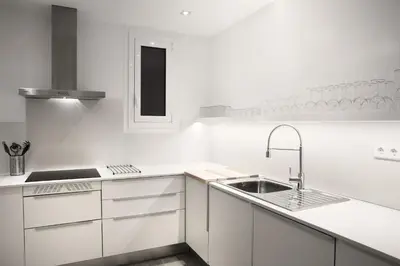 a white kitchen with white cabinets and a sink at Casanova Charm 4BDR Apartment in Barcelona