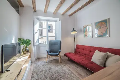a living room with a red couch and a tv at Welcomy Born in Barcelona