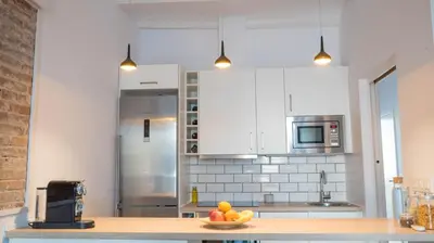 a kitchen with white cabinets and a bowl of fruit on a counter at Welcomy Poblenou II in Barcelona