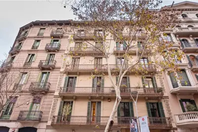 a tall building with balconies and a tree in front of it at Sweett - Ethnic Eixample in Barcelona