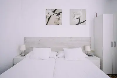 a white bedroom with a white bed and two lamps at Hostal Eixample in Barcelona