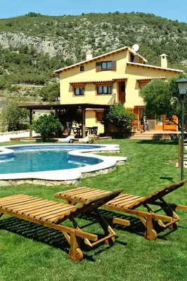 a house with a swimming pool and two wooden benches at La Ginesta Rural, cerca de Sitges in Canyelles