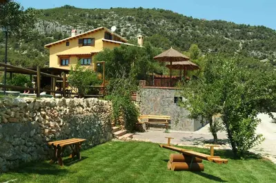 a house with a table and benches in the grass at La Ginesta Rural, cerca de Sitges in Canyelles