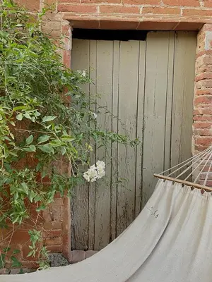a hammock sitting in front of a wooden door at L'ESTABLE DE CAN TABERNER in Bigues i Riells