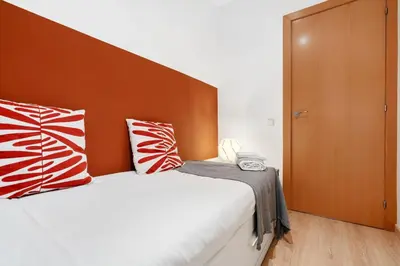 a bedroom with a bed with red and white pillows at Lodging Apartments Villarroel apartment in Barcelona