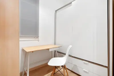 a white chair sits next to a desk in a room at Lodging Apartments Villarroel apartment in Barcelona