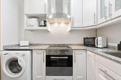 a kitchen with white cabinets and a washer and dryer at Lodging Apartments Villarroel apartment in Barcelona