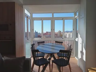 a table and chairs in a room with a large window at Ático cerca Playa y centro a 10 min. in Sant Adria de Besos